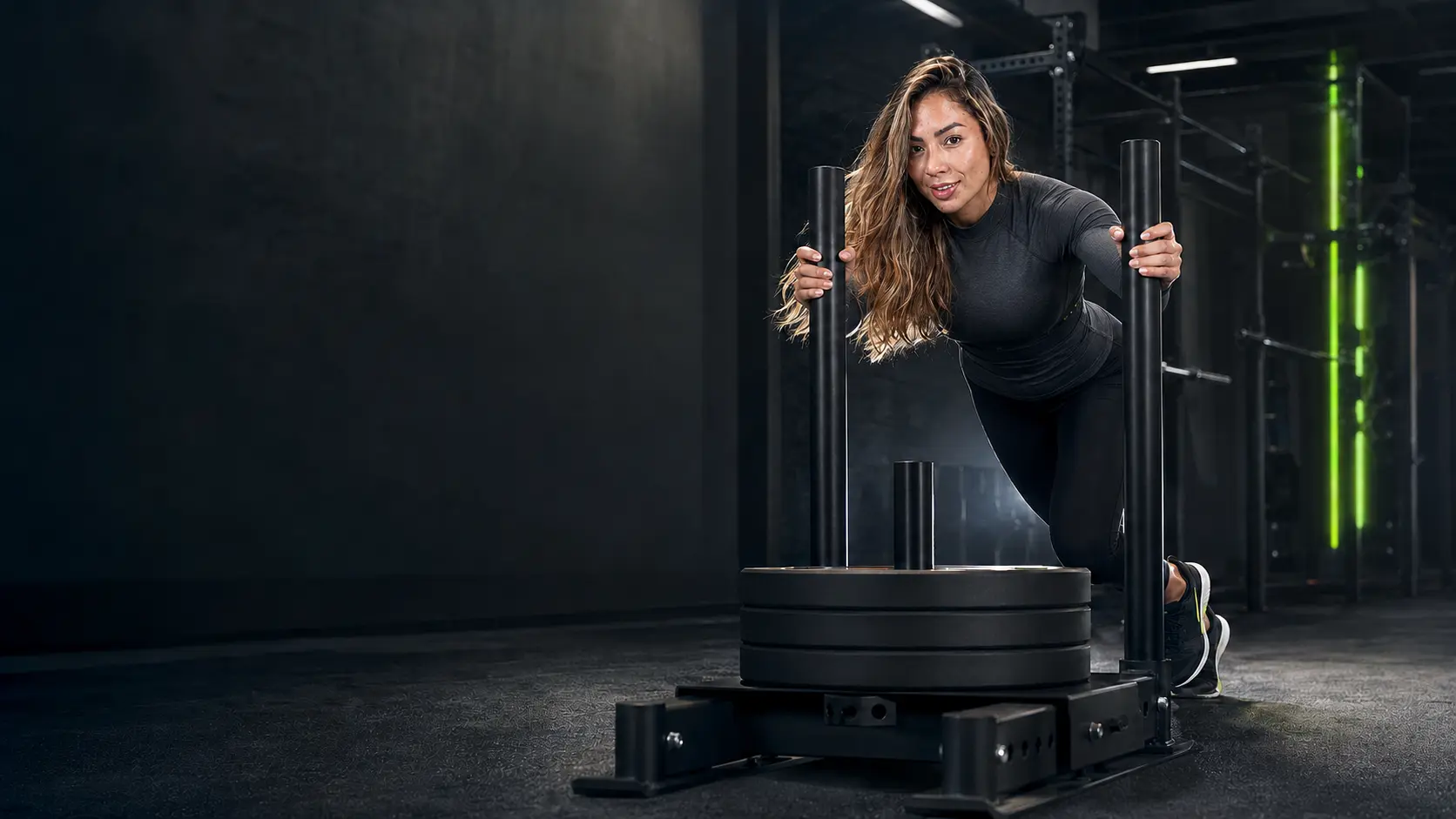 Mujer empujando un trineo cargado en un gimnasio